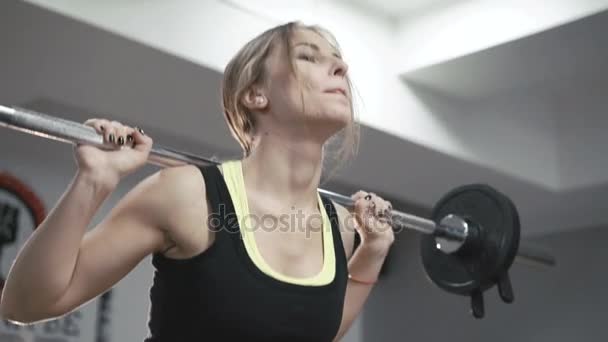 Primer plano de chica bonita haciendo ejercicio sentadillas con pesadas barras en el gimnasio en 4K — Vídeo de stock