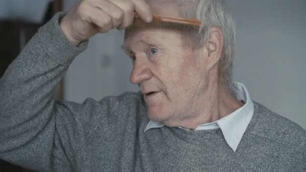 The senior is combing his short hair with a wooden comb 4K — Stock Video