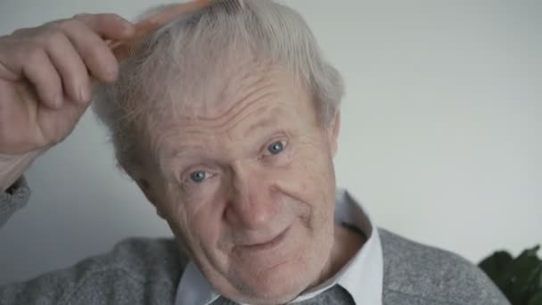 Pomarszczony senior jest czesanie jego siwe włosy z drewnianym grzebieniem 4k — Wideo stockowe