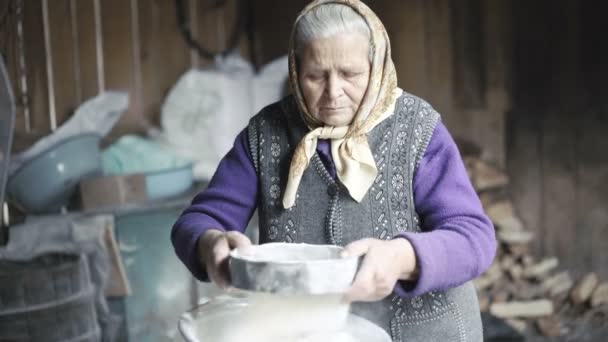 Wrinkled old woman sifting flour in barn in 4K — Stock Video