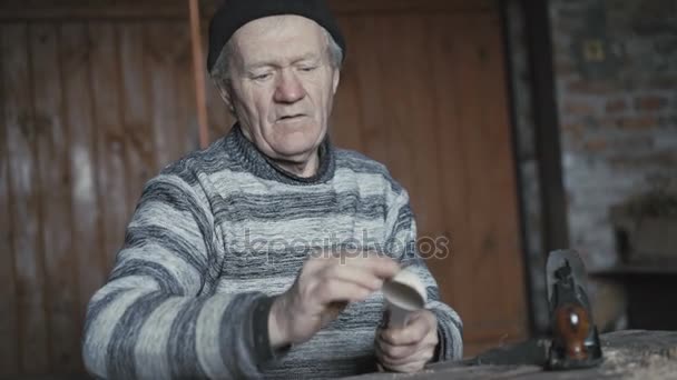Felice uomo rugoso tagliando il suo cucchiaio di legno fatto a mano e sorridendo alla fotocamera 4K — Video Stock