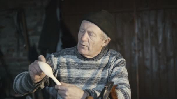 Старый морщинистый мужчина показывает свою деревянную ложку ручной работы и улыбается в камеру 4K — стоковое видео