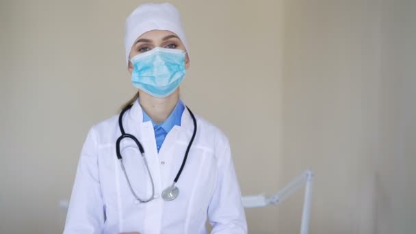 Женщина-медик в маске для лица смотрит в камеру — стоковое видео
