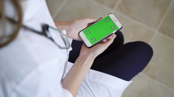 Женщина-врач показывает смартфон с зеленым экраном — стоковое видео