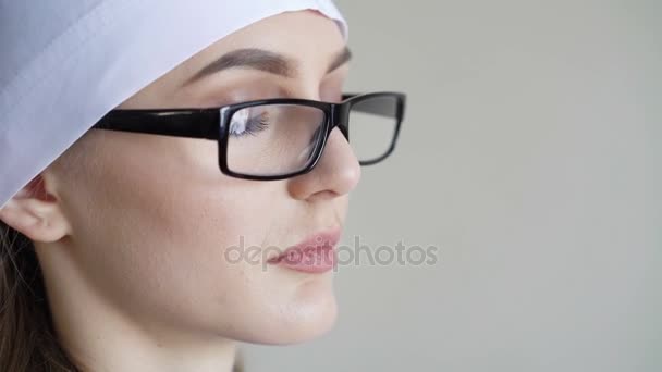 Portrait of a young adult female doctor with glasses, looking at camera — Stock Video