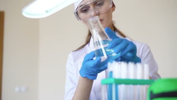 Unga kvinnliga kemist gör vetenskapligt experiment med kemikalier — Stockvideo