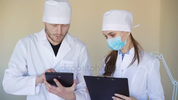 Médicos de aspecto serio que consultan algo sobre tableta — Vídeo de stock