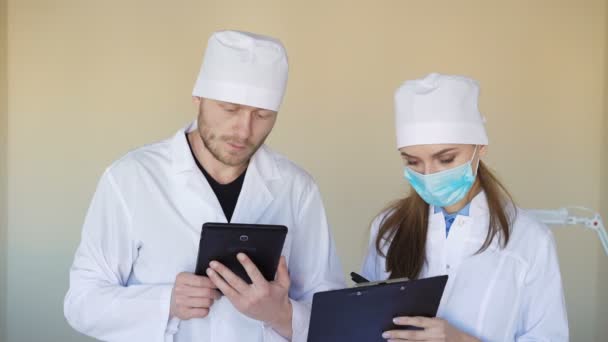 Médicos sérios consultando algo sobre tablet — Vídeo de Stock