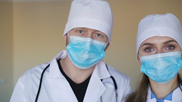 Νεαρός γιατρός θηλυκό και ένα αρσενικό γιατρό κοιτάζοντας την κάμερα — Αρχείο Βίντεο
