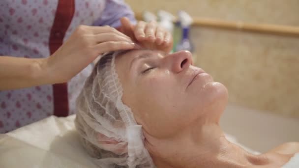 Mujer de mediana edad tomar cara y cuello linfático, masaje de drenaje en el salón de spa — Vídeos de Stock