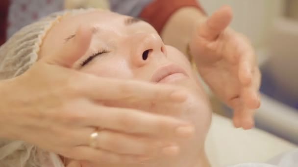 Нанесение крема на лицо и массаж в салоне красоты — стоковое видео