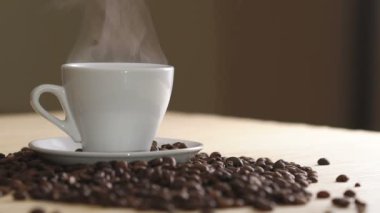 Buharlaşma kahve kavrulmuş fasulye yakınındaki masada beyaz bir fincan kapatmak