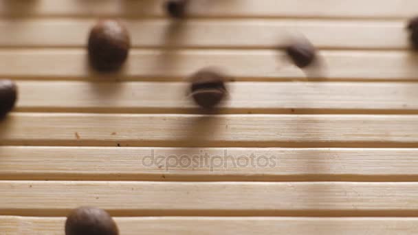 Granos de café tostados cayendo sobre la superficie de la mesa en 4K — Vídeo de stock