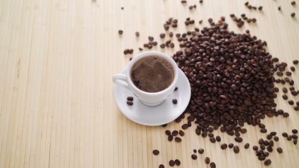 Una taza blanca de café evaporando sobre la mesa con frijoles asados en 4K — Vídeos de Stock