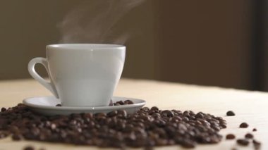 Buharlaşma kahve kavrulmuş fasulye yakınındaki masada beyaz fincan kapatın. Yavaş yavaş