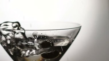 Alkol ile belgili tanımlık bardak içine düşen bir zeytin. Yavaş yavaş