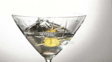 Alkol ile belgili tanımlık bardak içine düşen bir zeytin. Yavaş yavaş