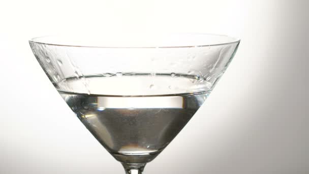 Una aceituna cayendo en la copa con el alcohol. Despacio. — Vídeo de stock