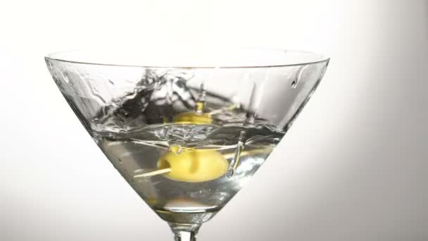 Una aceituna cayendo en la copa con el alcohol. Despacio. — Vídeos de Stock