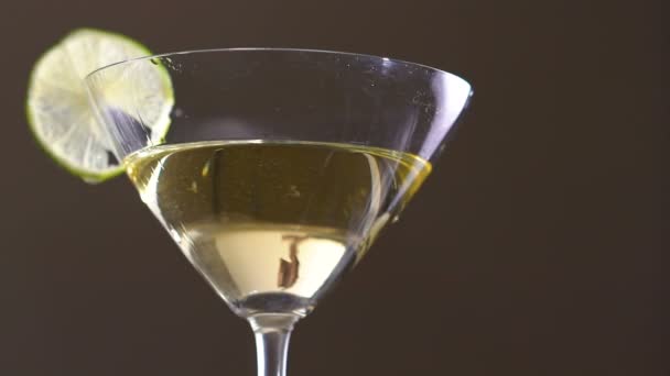 Eine Olive, die mit Alkohol und Limettenscheiben in den Becher fällt. langsam — Stockvideo