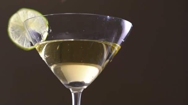 Une olive tombant dans le gobelet avec l'alcool et la tranche de citron vert. Doucement. — Video