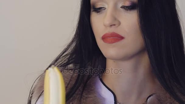 Vurige brunette een grote banaan pellen en kijken naar de camera. Langzaam — Stockvideo