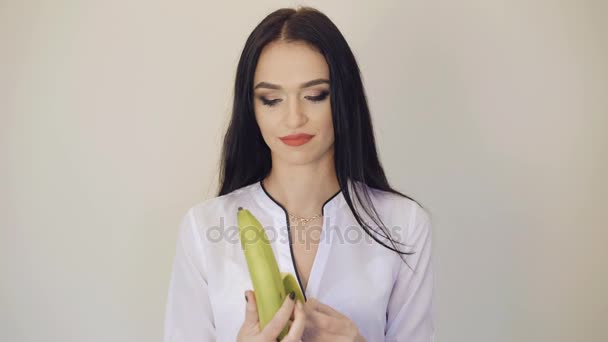 Linda chica pelando y un plátano grande y sonriendo a la cámara 4K — Vídeo de stock