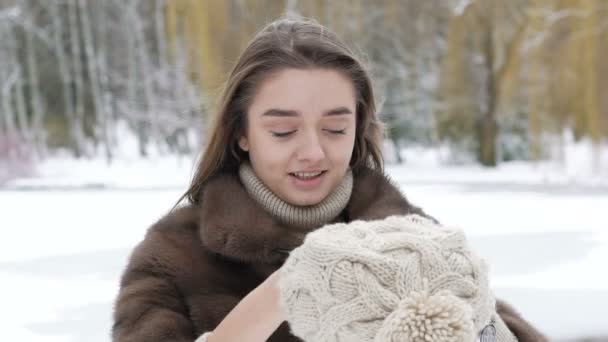 Jovem menina inteligente colocando chapéu de inverno no parque. Devagar. — Vídeo de Stock