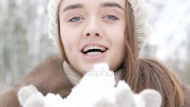 Gros plan portrait de belle fille heureuse soufflant de la neige en plein air. Doucement. — Video