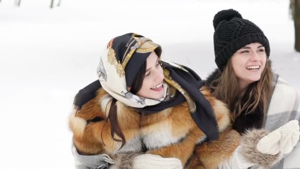 Dos chicas cubiertas de cuadros abrazándose y sonriendo en el parque de invierno. Despacio. — Vídeo de stock