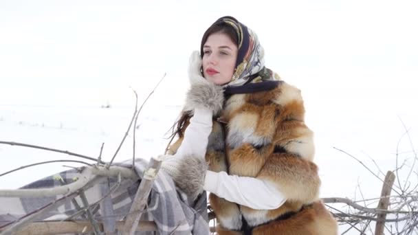 Menina jovem em roupas de inverno esperando perto de cerca e olhando para o lado 4K — Vídeo de Stock