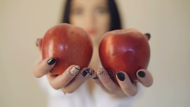 Filles mains tient deux grosses pommes rouges devant la caméra, fond flou 4K — Video