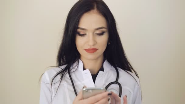 Atractivo médico femenino utilizando el teléfono móvil en el fondo 4K — Vídeos de Stock