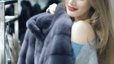 Güzel kız bir kürk manto dükkanda yavaş yavaş seçer
