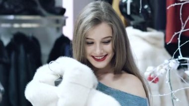 Güzel kız bir kürk manto dükkanda yavaş yavaş seçer