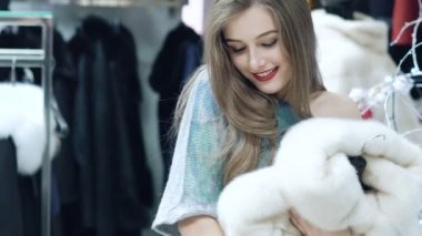 Güzel kız bir kürk manto dükkanda yavaş yavaş seçer