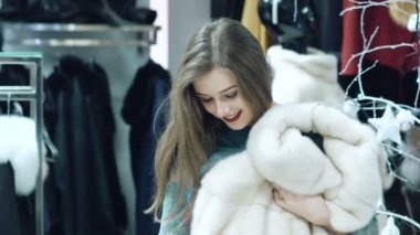 Güzel kız bir kürk manto dükkanda yavaş yavaş seçer