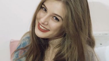 Güzel kız yatak arka plan üzerinde duygularla kamera için poz. Yavaş yavaş