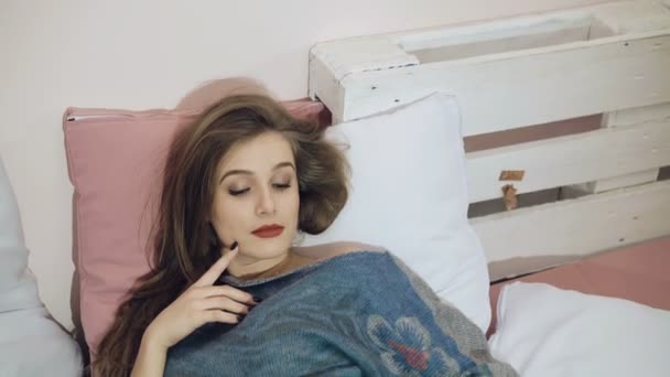 Красивая девушка отдыхает на современной кровати в 4K — стоковое видео