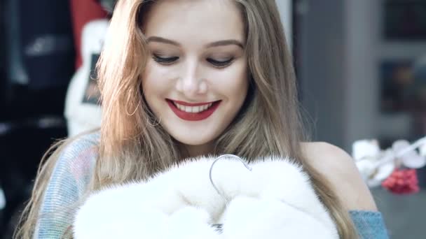 Красива дівчина вибирає шубу в магазині Повільно — стокове відео