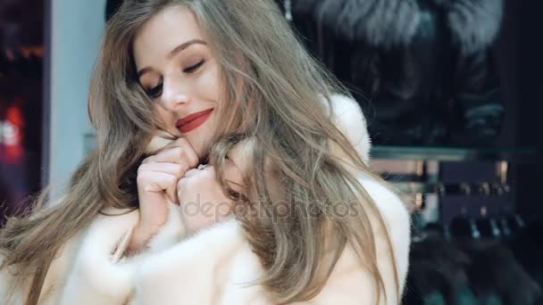 Happy girl trying on and posing in fur coat in the shop. Slowly — Stock Video