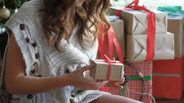 Glad flicka som leker med gåvor på golvet nära julgran långsamt — Stockvideo