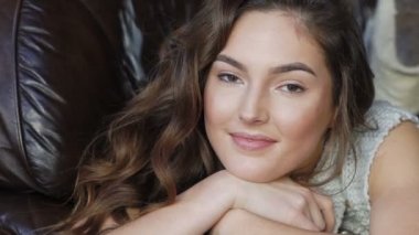 Rahatlatıcı ve deri kanepede gülümseyen güzel kız