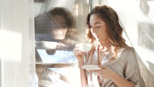 Відображення у вікні жінки, що п'є чашку напою 4K — стокове відео