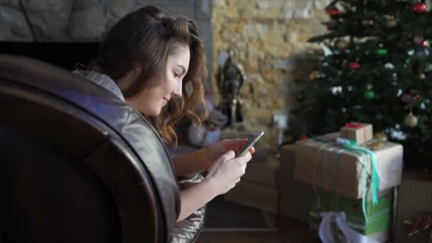 Csinos lány a bőr kanapé pihentető és használ mozgatható telefon 4k — Stock videók