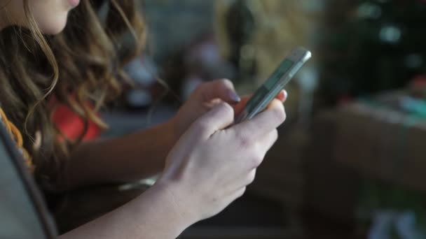 Закройте красивую девушку, отдыхающую на кожаном диване и пользующуюся мобильным телефоном 4K — стоковое видео
