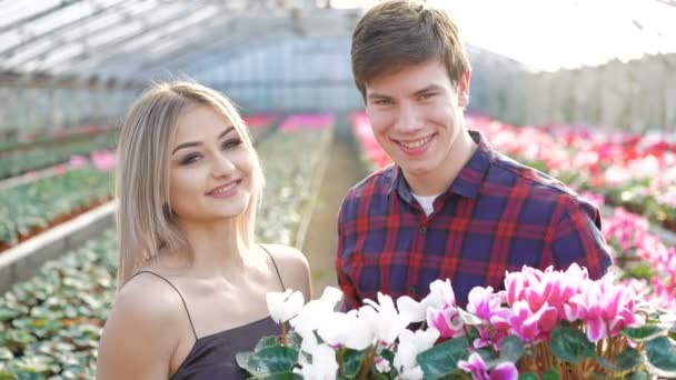 Male and female gardeners smiling to camera on flowers background 4K — Stock Video