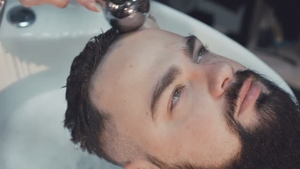 Молодой хипстер моет голову в парикмахерской. 4K — стоковое видео