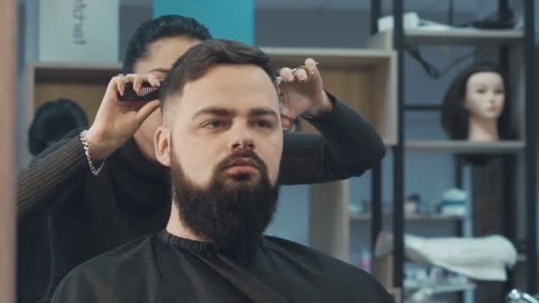 Female haircutter cutting the male hair in the barbershop — Stock Video