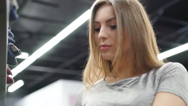 Menina elegante olhando para a roupa na boutique elegante. 4K — Vídeo de Stock
